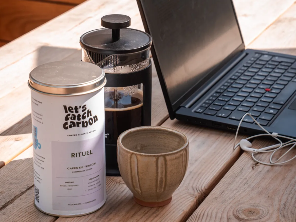 Cafetière à piston et tasse en grès avec café en boîte sur une table en bois