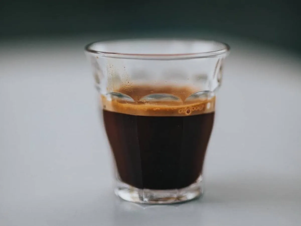 Espresso serré avec crema dans un verre, plus concentré mais moins caféiné qu'un café filtre