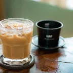 Café glacé vietnamien au lait concentré dans un verre, à côté d'un filtre phin en métal
