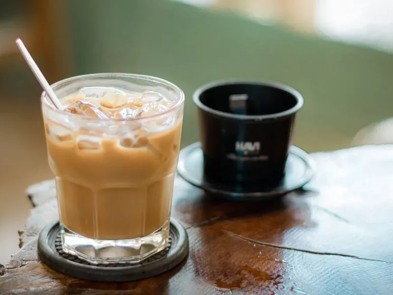 Café glacé vietnamien au lait concentré dans un verre, à côté d'un filtre phin en métal