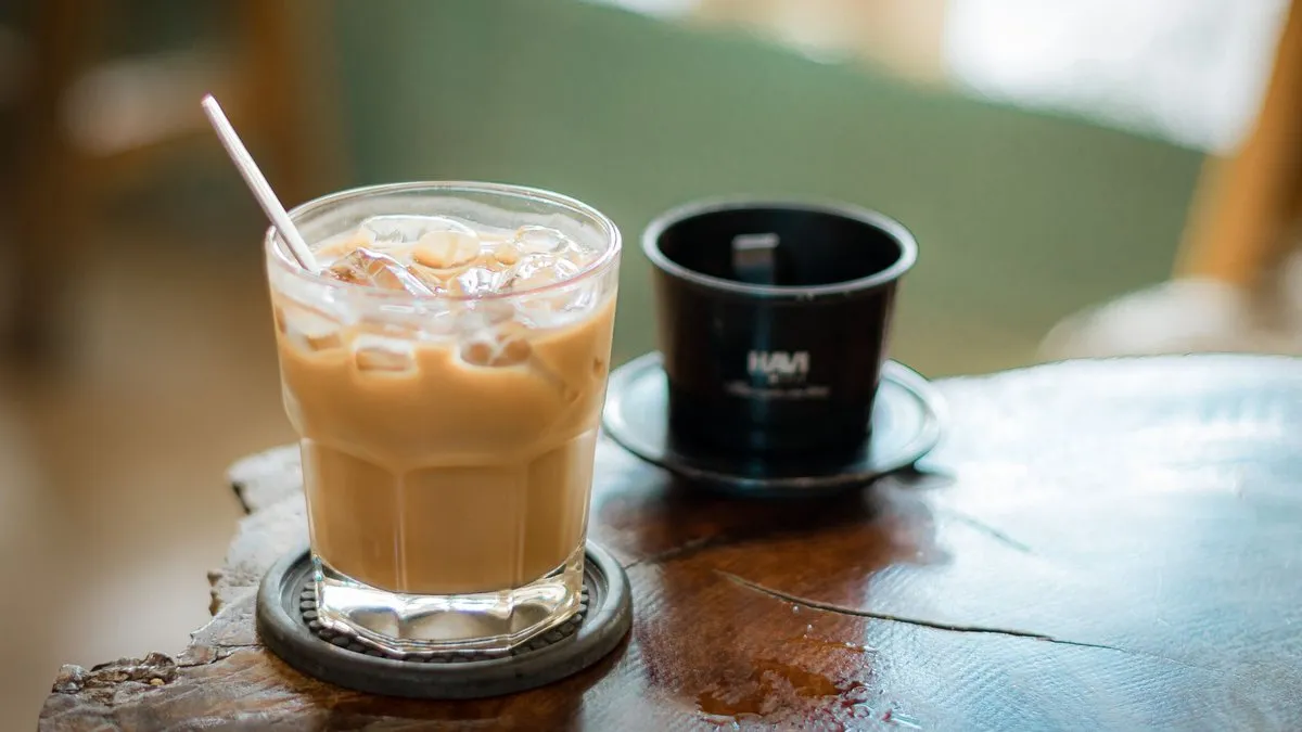 Café glacé vietnamien au lait concentré dans un verre, à côté d'un filtre phin en métal