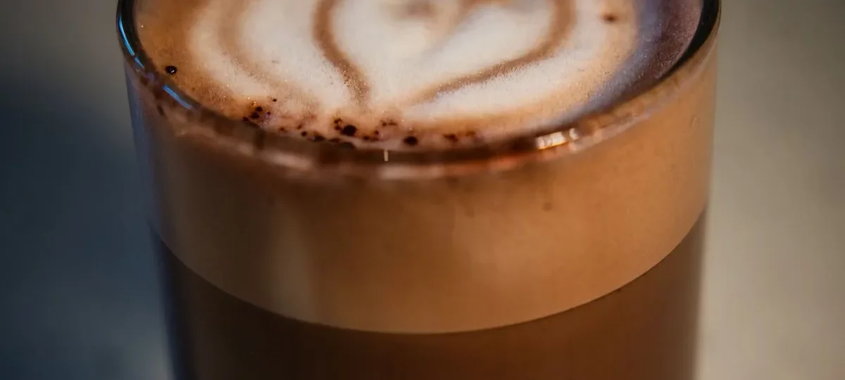 Café macchiato en petit verre, espresso taché d'une touche de mousse de lait en forme de cœur