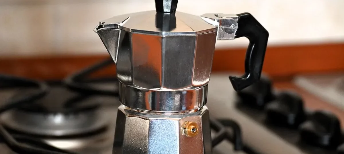Cafetière italienne moka en aluminium posée sur une gazinière, prête à préparer le café