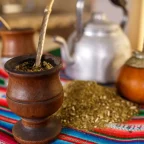 Calebasses de maté remplies de yerba avec leur bombilla, yerba en vrac et bouilloire sur un tissu andin