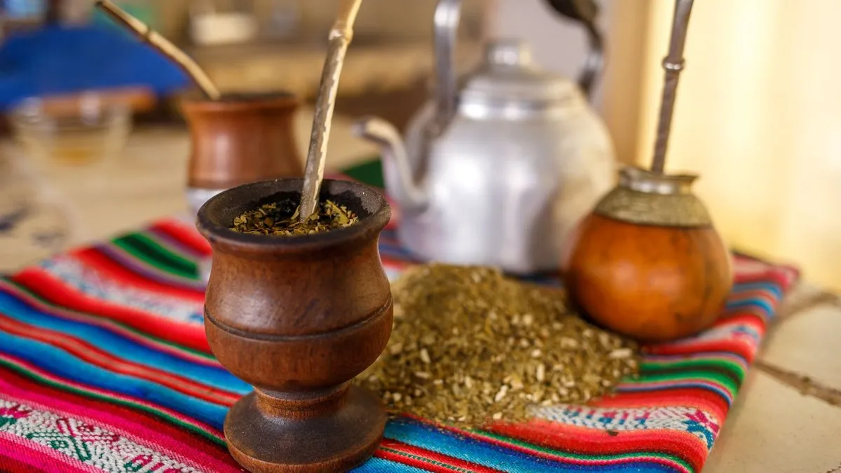 Calebasses de maté remplies de yerba avec leur bombilla, yerba en vrac et bouilloire sur un tissu andin
