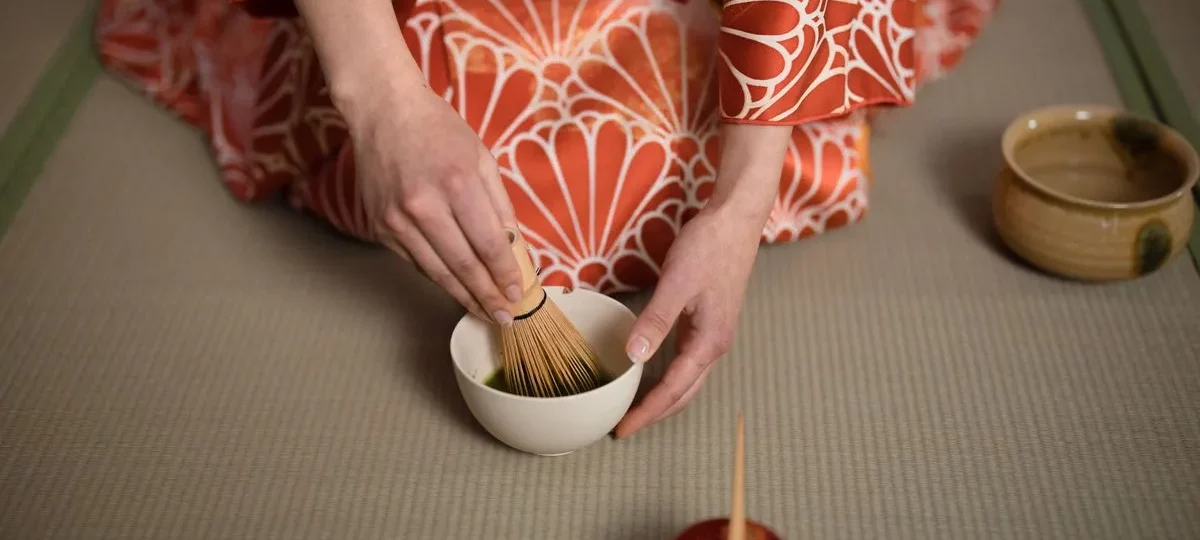 Cérémonie du thé japonaise : matcha fouetté au chasen dans un bol, par une personne en kimono sur tatami