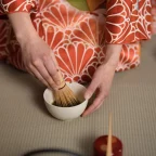 Cérémonie du thé japonaise : matcha fouetté au chasen dans un bol, par une personne en kimono sur tatami