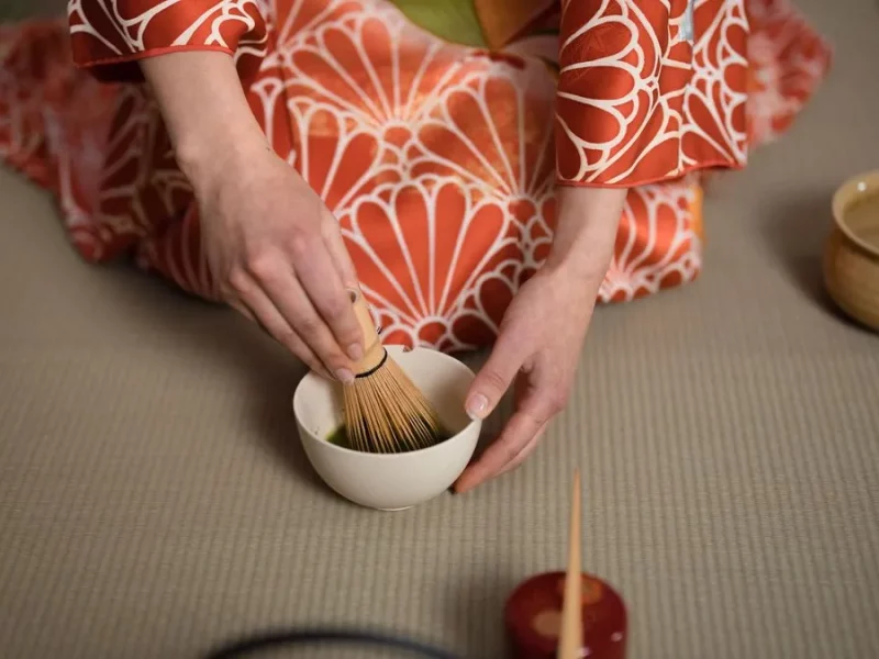 Cérémonie du thé japonaise : matcha fouetté au chasen dans un bol, par une personne en kimono sur tatami