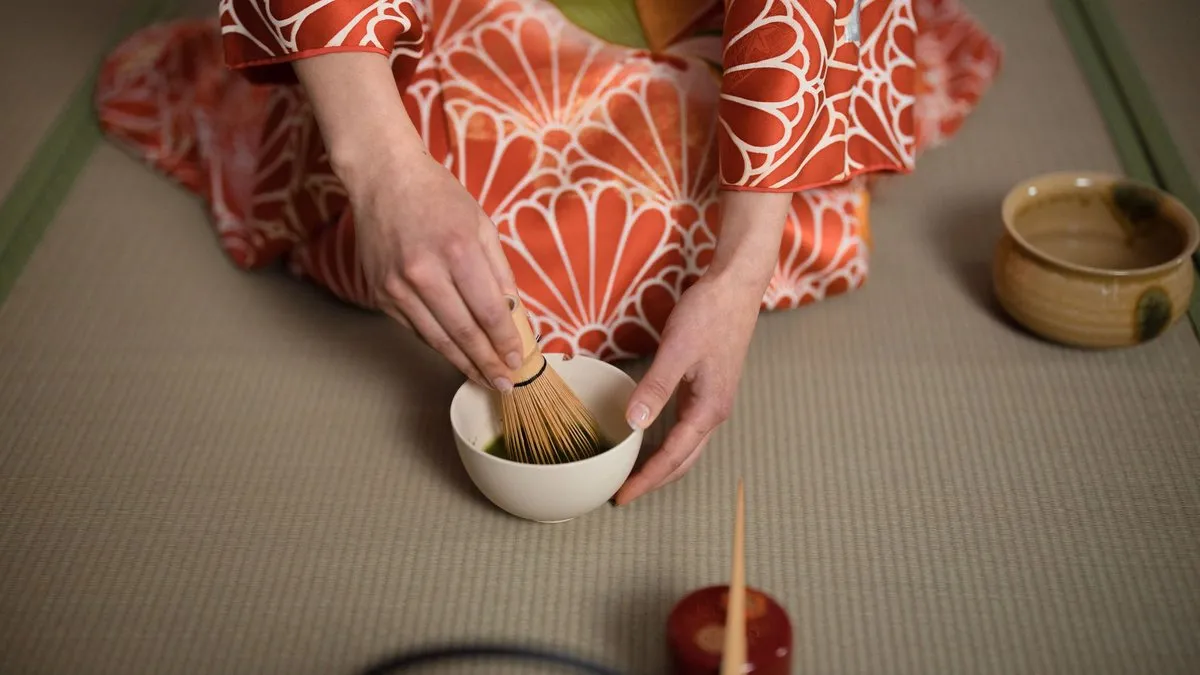 Cérémonie du thé japonaise : matcha fouetté au chasen dans un bol, par une personne en kimono sur tatami