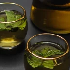 Deux verres d'infusion à la menthe fraîche et une théière en verre sur fond sombre
