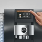 Doigt réglant la finesse de mouture et l'intensité du café sur l'écran tactile d'une machine à café Jura Z10