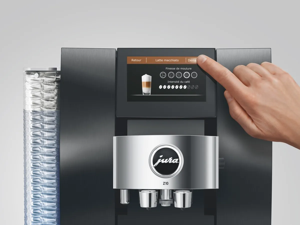 Doigt réglant la finesse de mouture et l'intensité du café sur l'écran tactile d'une machine à café Jura Z10