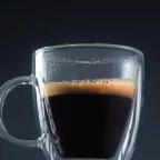 Doppio, double expresso à la crema dorée dans une tasse en verre sur fond sombre