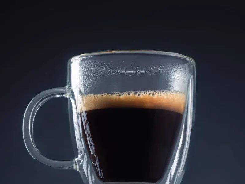 Doppio, double expresso à la crema dorée dans une tasse en verre sur fond sombre