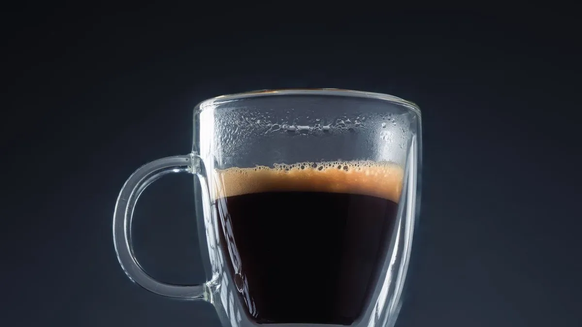 Doppio, double expresso à la crema dorée dans une tasse en verre sur fond sombre