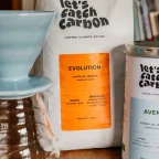 Dripper Hario V60 bleu posé sur une carafe en verre, avec un sachet et une boîte de café en grains