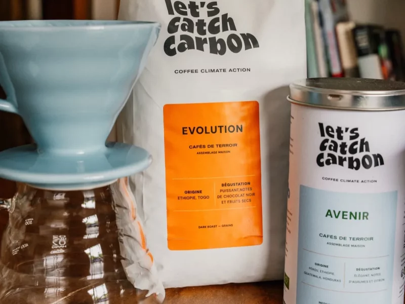 Dripper Hario V60 bleu posé sur une carafe en verre, avec un sachet et une boîte de café en grains