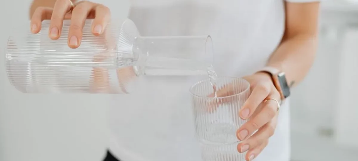 Eau versée d'une carafe dans un verre, l'eau filtrée qui limite le calcaire dans la machine