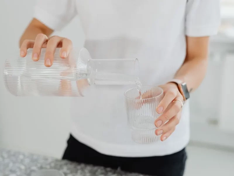 Eau versée d'une carafe dans un verre, l'eau filtrée qui limite le calcaire dans la machine