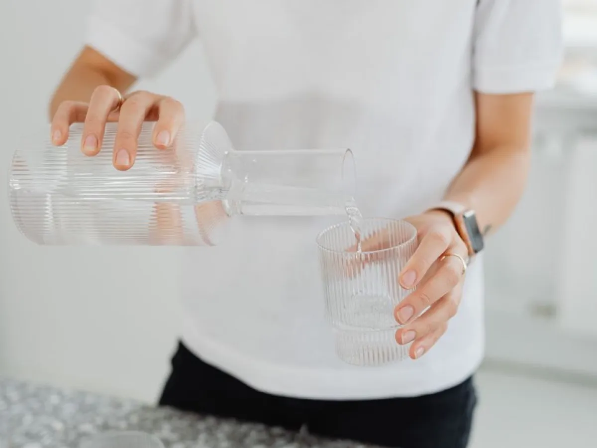Eau versée d'une carafe dans un verre, l'eau filtrée qui limite le calcaire dans la machine