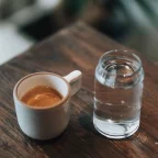 Espresso et verre d'eau posés sur une table en bois, l'eau étant à l'origine du calcaire