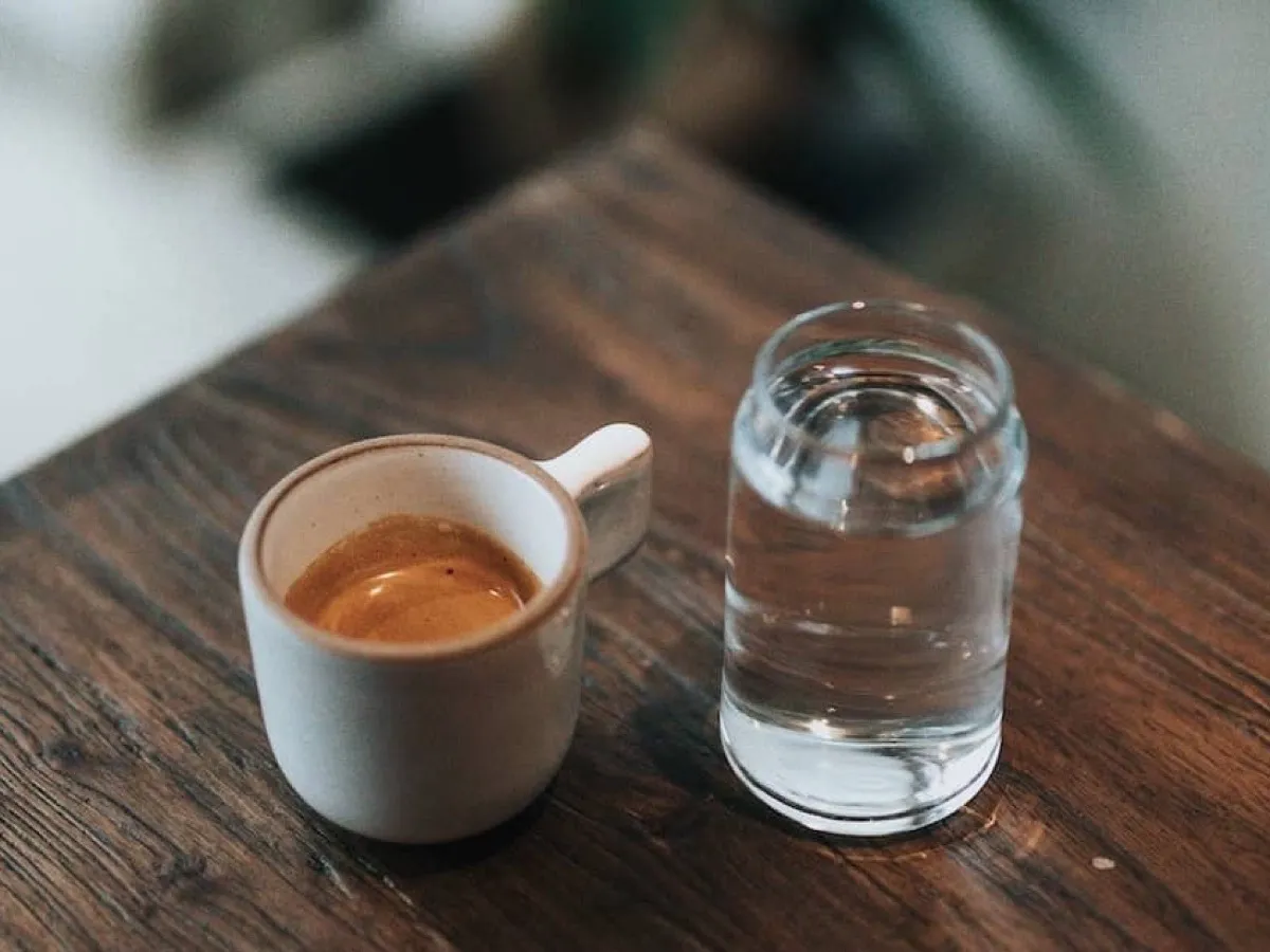 Espresso et verre d'eau posés sur une table en bois, l'eau étant à l'origine du calcaire