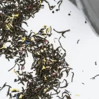 Feuilles de thé Earl Grey en vrac aux pétales de bleuet versées d'un sachet vers une tasse