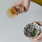 Fouet chasen en bambou tenu au-dessus d'un bol de matcha en cours de préparation
