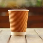 Gobelet de café chaud fumant posé sur une table en bois