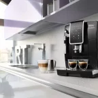 Machine à café à grains De'Longhi Dinamica noire dans une cuisine moderne, deux tasses servies