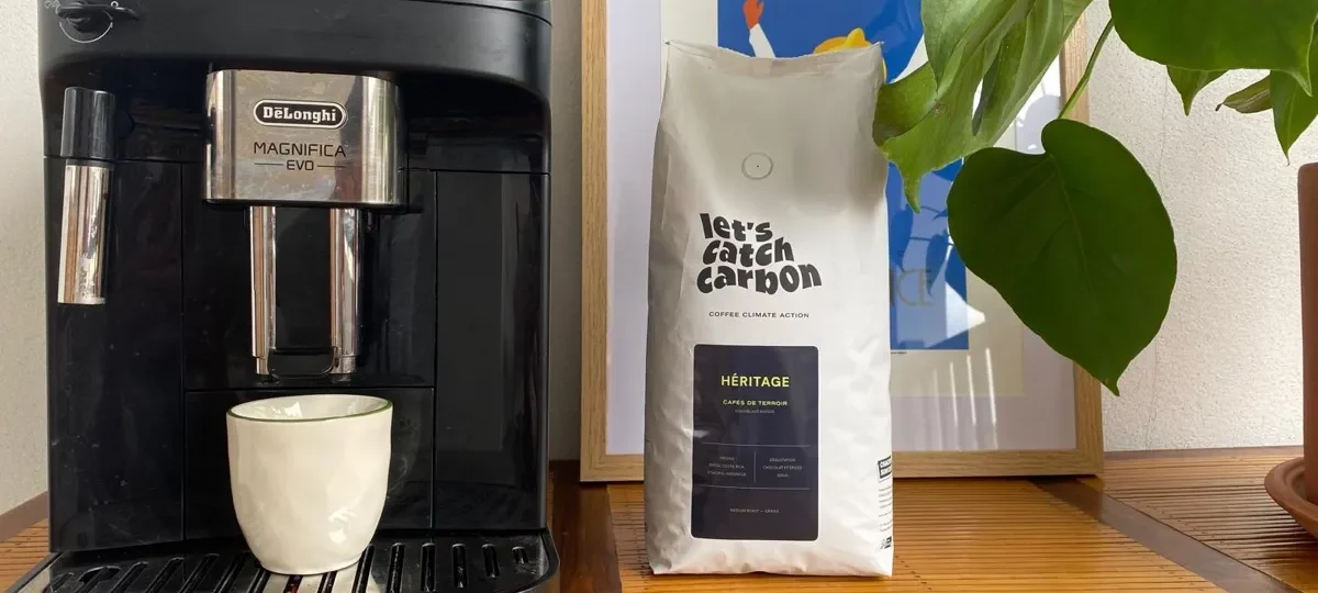 Machine à café à grains De'Longhi Magnifica Evo avec tasse sous la buse, à côté d'un sachet de café en grains