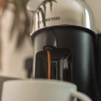 Machine Nespresso Vertuo chromée versant un café dans une tasse blanche, avant son détartrage