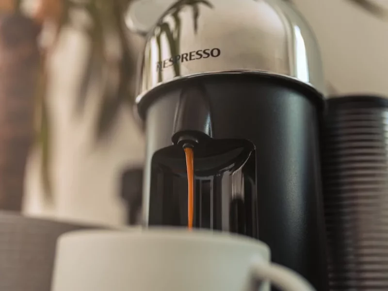 Machine Nespresso Vertuo chromée versant un café dans une tasse blanche, avant son détartrage