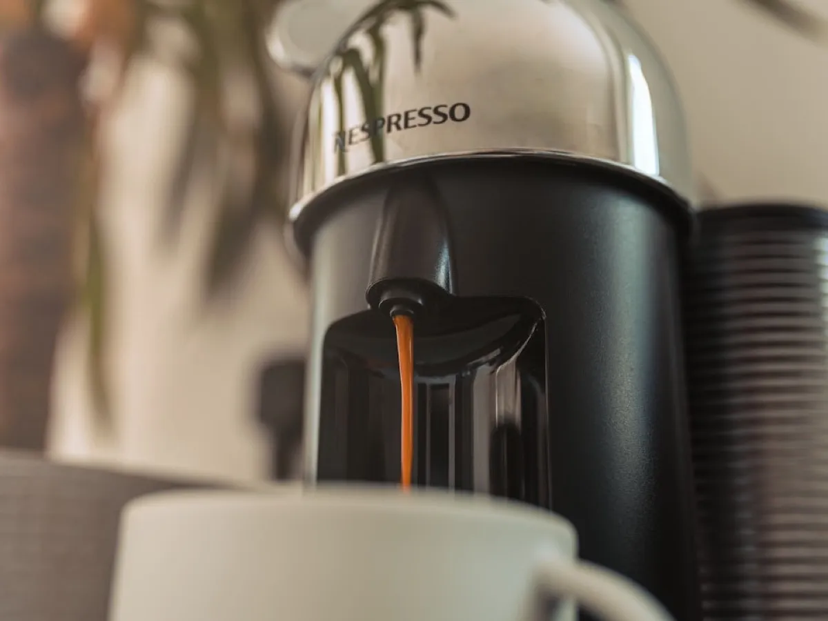Machine Nespresso Vertuo chromée versant un café dans une tasse blanche, avant son détartrage