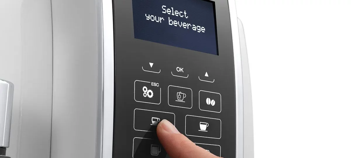 Doigt sélectionnant une boisson sur le panneau de commande d'une machine à grains De'Longhi