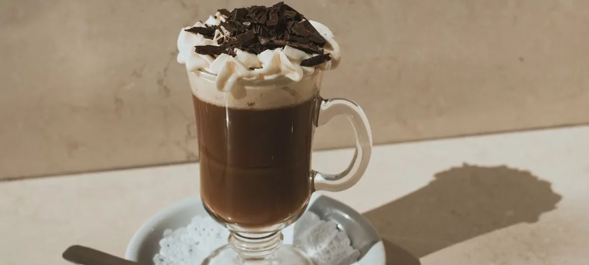 Mocaccino en verre à anse surmonté de mousse de lait et de copeaux de chocolat