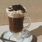 Mocaccino en verre à anse surmonté de mousse de lait et de copeaux de chocolat