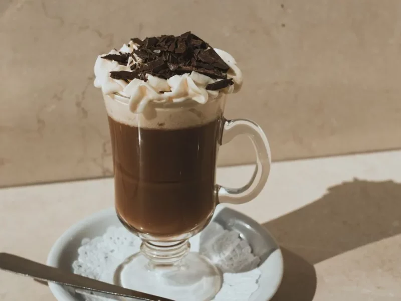 Mocaccino en verre à anse surmonté de mousse de lait et de copeaux de chocolat