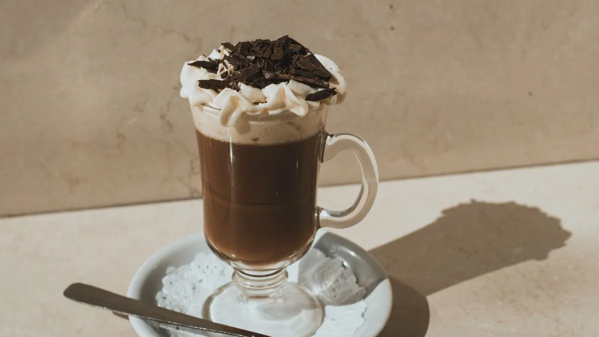 Mocaccino en verre à anse surmonté de mousse de lait et de copeaux de chocolat