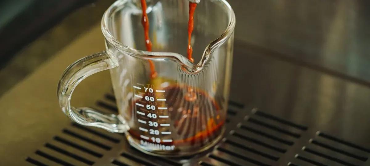 Ristretto qui coule d'un porte-filtre dans un verre doseur gradué sur la grille d'une machine à expresso