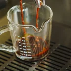 Ristretto qui coule d'un porte-filtre dans un verre doseur gradué sur la grille d'une machine à expresso