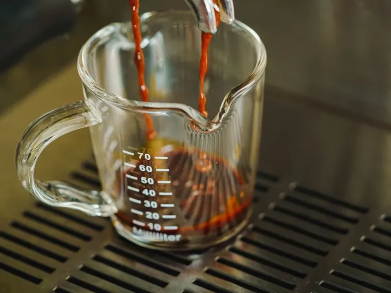 Ristretto qui coule d'un porte-filtre dans un verre doseur gradué sur la grille d'une machine à expresso
