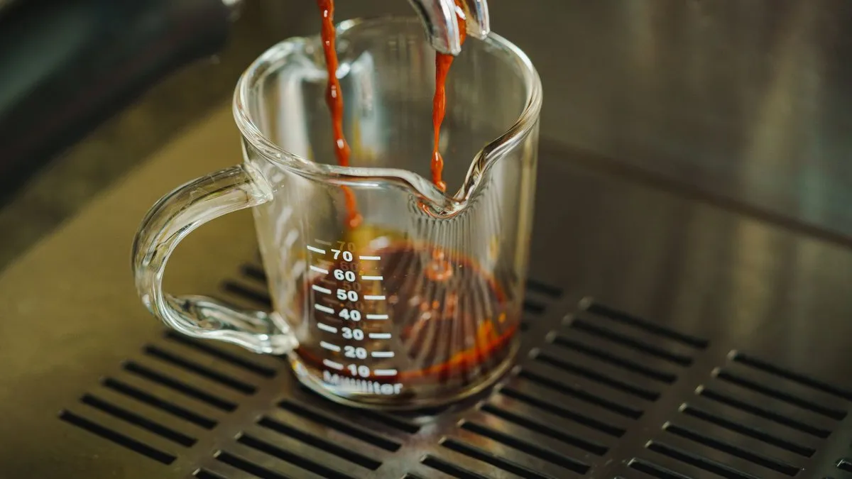 Ristretto qui coule d'un porte-filtre dans un verre doseur gradué sur la grille d'une machine à expresso