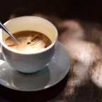 Tasse de café au lait avec une cuillère sur une table en bois, lumière chaude
