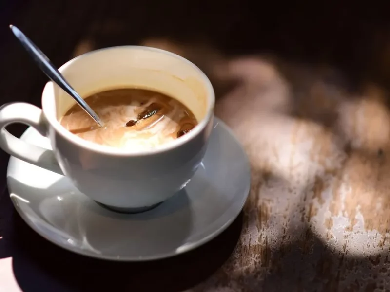 Tasse de café au lait avec une cuillère sur une table en bois, lumière chaude