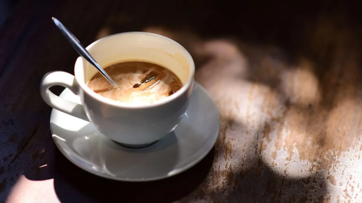 Tasse de café au lait avec une cuillère sur une table en bois, lumière chaude