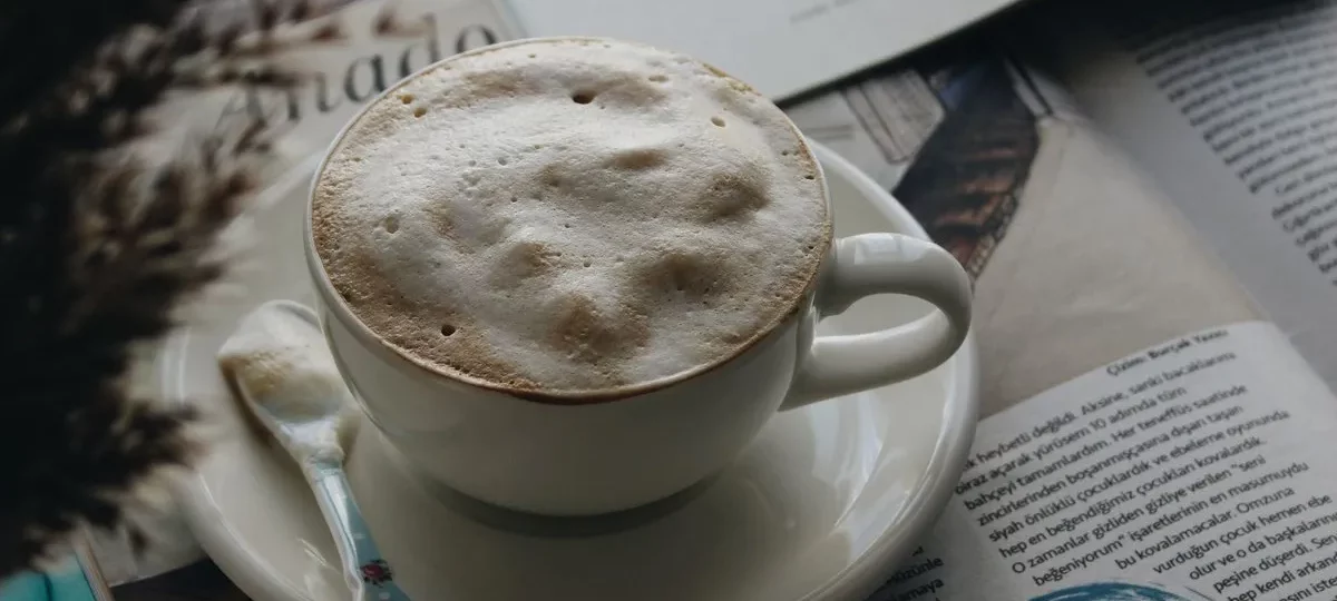 Tasse de café crème à la mousse épaisse posée sur un journal ouvert