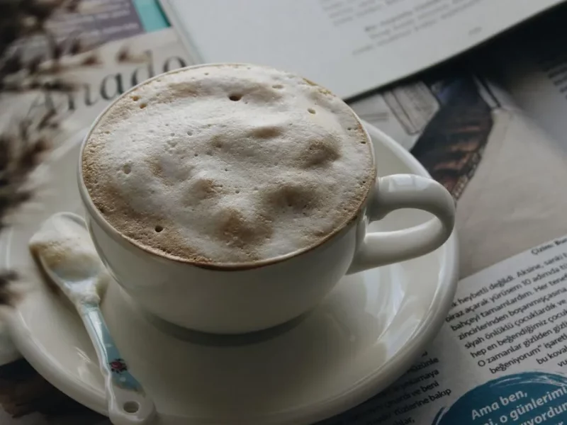 Tasse de café crème à la mousse épaisse posée sur un journal ouvert