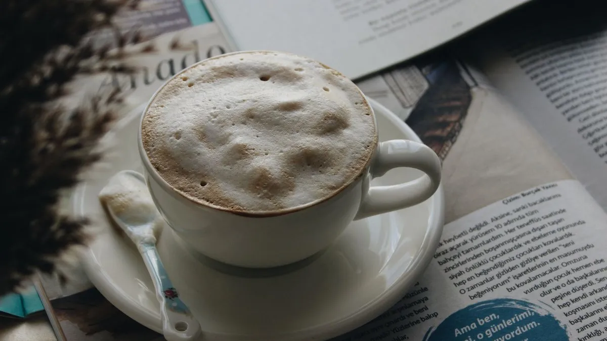 Tasse de café crème à la mousse épaisse posée sur un journal ouvert