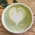 Tasse de matcha latte avec un cœur en mousse de lait, vue de dessus sur une table en bois